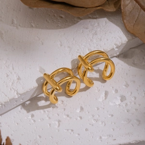 Detailed view of gold multi-layer line wrap ear cuffs on a white textured stone base