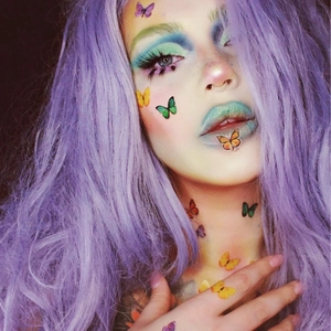 Vibrant butterfly tattoo stickers for face and body on a model with purple wig