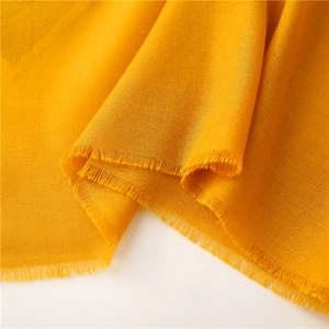 Primer plano de bufanda amarillo jengibre con textura fina y detalles de bordes deshilachados