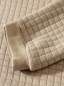 Detailed macro view of khaki quilted fabric texture and elastic ribbed knit cuffs