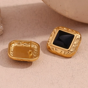 Macro detail of square black acrylic studs with hammered 18K gold plated texture