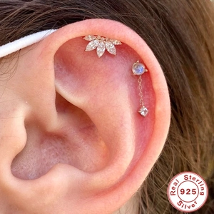 Close-up of S925 sterling silver paw print and flower piercing stud on ear with moonstone