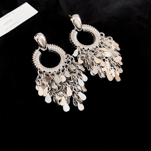 Detail of silver round earrings with dangling leaf tassels on black velvet background