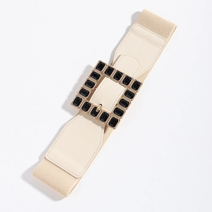 Detailed view of beige elastic belt with large gold buckle and black acrylic gems