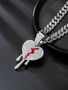 Macro shot of silver Cuban link chain with a rhinestoned broken heart pendant and red drip