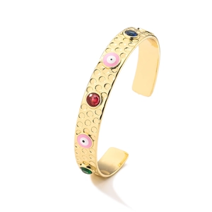 Detailopname van de gouden open armband met gekleurde edelstenen en roze boze oog emaille
