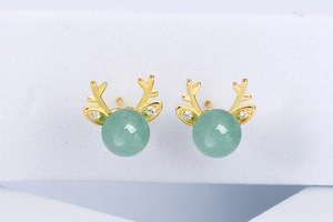Detailed close-up of gold reindeer antler stud earrings with green beads and diamonds