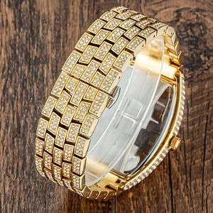Close-up of gold-tone iced out watch band with sparkling crystals on wooden surface