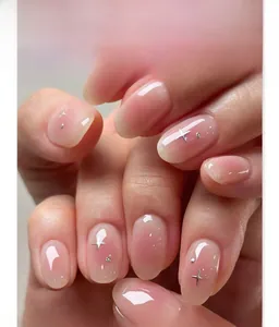 Close-up of pink blush gradient press-on nails with silver star charms and round accents
