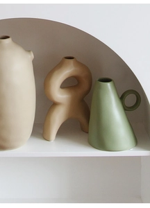 Three-piece matte ceramic vase set in Morandi colors displayed on an arched white shelf