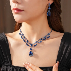 Detail of silver drop necklace and earrings set with deep blue zircon stones on model