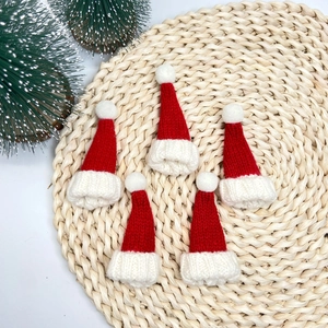 Vue détaillée de cinq mini bonnets de Noël tricotés rouges avec pompons blancs sur une natte