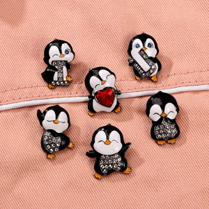 Set of 7 cartoon penguin enamel brooches with rhinestones and red heart on pink fabric