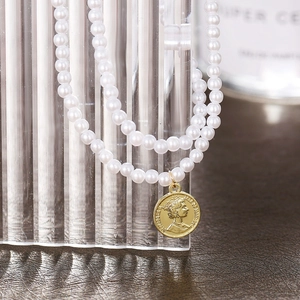 Detail of double-layer pearl necklace with a gold Queen Elizabeth coin pendant