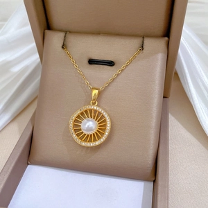 Close-up of 18K gold hollow pendant necklace with center pearl and sparkling zircon details