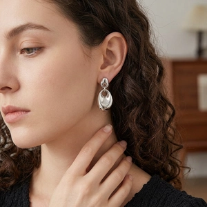 Minimalist irregular liquid metal drop earrings in silver finish worn by a model