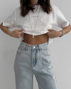 Détail du jean bleu clair à taille haute avec bouton en métal et texture lavée