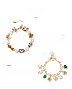 Detail of vintage gold bracelets with evil eye pendants and pearl charms on white background