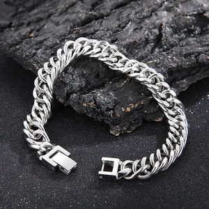 Détail d'un bracelet gourmette cubain en acier inoxydable argenté sur un fond texturé sombre