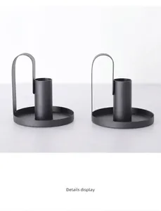 Detail of minimalist black matte iron candlesticks with round base and arc handle