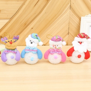 Close-up of four plush Christmas ornaments featuring reindeer, snowmen, and bears on wood