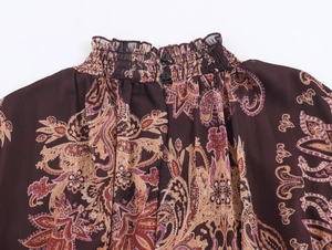 Macro view of back collar with paisley print, ruffled high neck and button closure