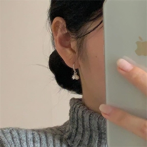 Close-up of 925 silver earring with crown setting and elegant pearl on female ear