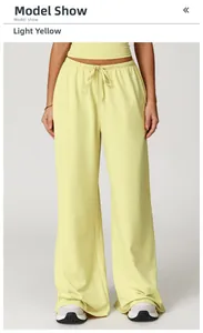 Detail of light yellow wide-leg trousers featuring elastic waistband and drawstring cords