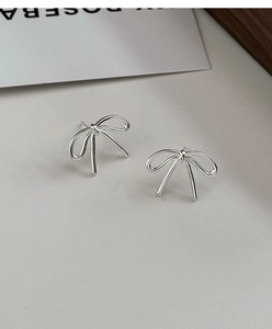 Macro shot of silver bow stud earrings on a minimalist background card