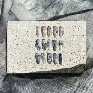 Artistic press-on nails with Chinese calligraphy and marble texture on stone display