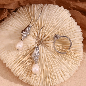 Detail of 18K silver plated shell earrings and ring with pearls on coral stand