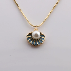 Gold plated shell pendant necklace with blue enamel and pearl on reflective background