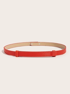 Detail view of red slim leather belt with cross pattern texture and silver buckle