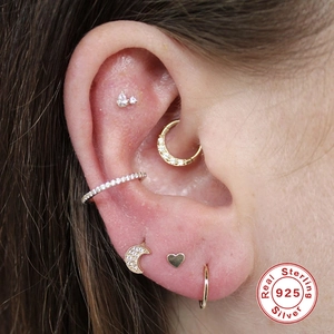 Detail view of gold S925 sterling silver ear piercings with crystal studs and hoop rings