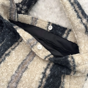 Close-up of magnetic buckle closure on a plush plaid tote bag with warm woolly texture