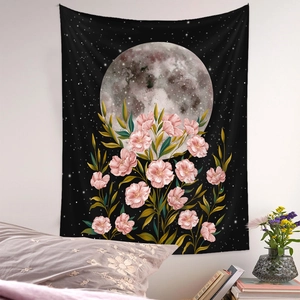 Artistic moon phase tapestry with pink floral design hanging on a cozy bedroom wall