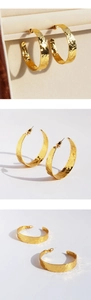 Macro detail of gold C-shaped hoop earrings featuring unique hammered crinkle texture