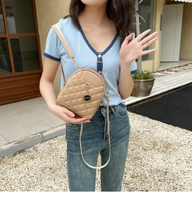 Quilted crossbody bag with cat pendant shown on model in street style outdoor setting
