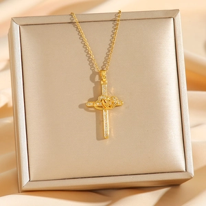Gold cross necklace with interlocking heart pendant and pavé crystals on silk background