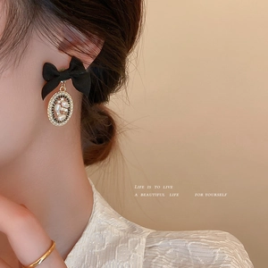 French vintage earrings with black bow and pearl pendant shown on a model side profile