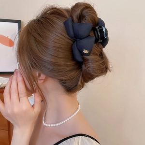 Detail of elegant black satin bow hair claw clip worn on a low bun hairstyle