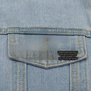 Five black enamel sarcasm quote pins displayed on a light blue denim jacket pocket