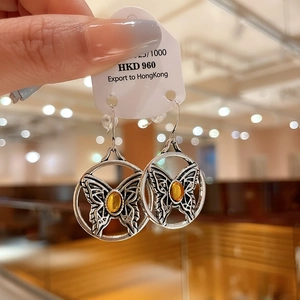 Macro detail of silver vintage earring featuring hollow butterfly and yellow gemstone