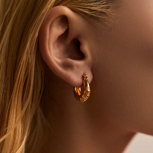 18K gold plated brass hoop earrings with grainy textured design on a model