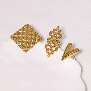 Detailed view of three-piece gold stainless steel rings with heart and chain patterns