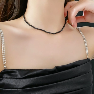 Detail of a minimalist black crystal beaded choker necklace worn on a model's neck