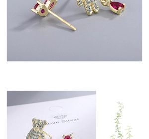 Detail of golden bear earrings with red drop-shaped gemstone and white cubic zirconia