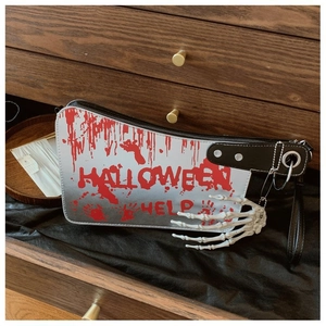 Detail of cleaver-shaped bag with Halloween Help text and skeletal hand charm in a drawer