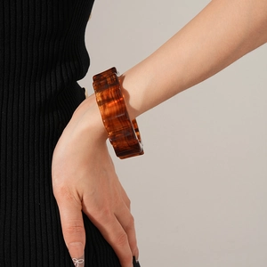 Close-up of a thick amber tortoiseshell resin cuff bracelet with square faceted edges