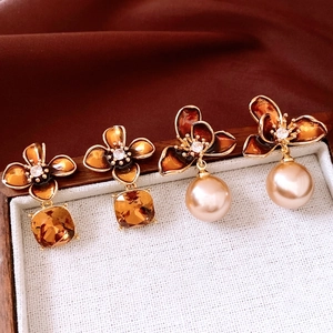 Detail view of flower earrings with amber crystals, cubic zirconia, and round pearls